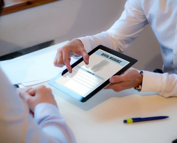 Oral surgeon and patient looking at dental insurance forms on tablet computer