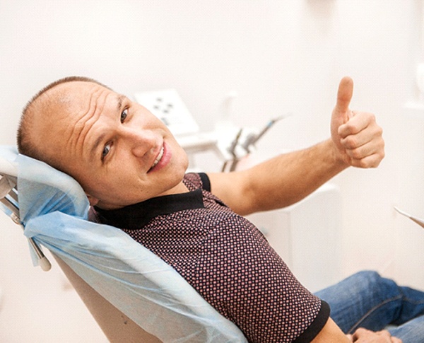Man giving thumbs up while sitting in dental chair