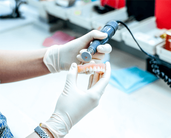 dental lab technician polishing denture