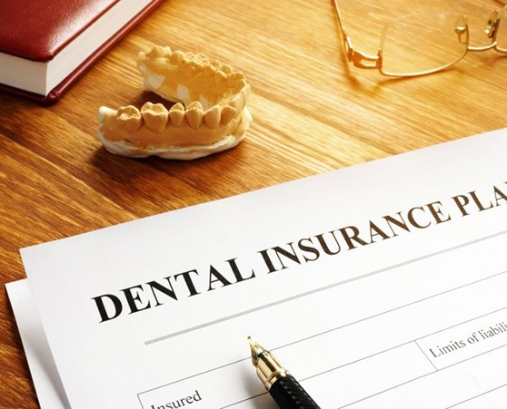 a dental insurance form next to a wax model of teeth