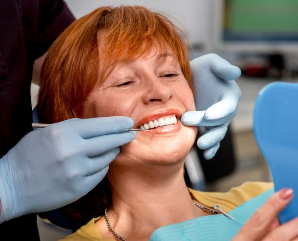 Woman looking at smile after all on four dental implants placement