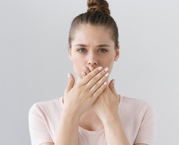 a woman covering her broken front tooth in Coppell