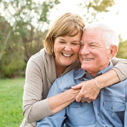 Older couple smiling with arms around each other outside