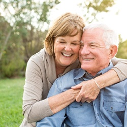 Older couple smiling with arms around each other outside