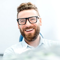 Man with beard and glasses smiling in dental chair