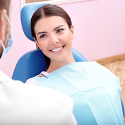 Woman with brown hair sitting in dental chair smiling