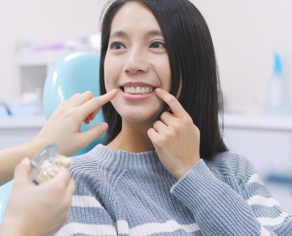 Dentist showing patient a dental implant model