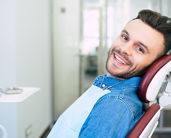 Male patient in denim jacket leaning back in chair and smiling