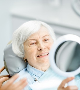 older woman in dental chair looking in mirror
