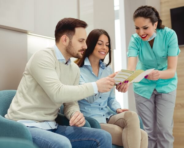 Patients reviewing dental insurance information with oral surgery team member