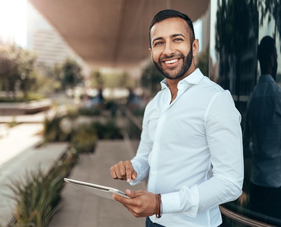 Man standing outside office building holding a tablet