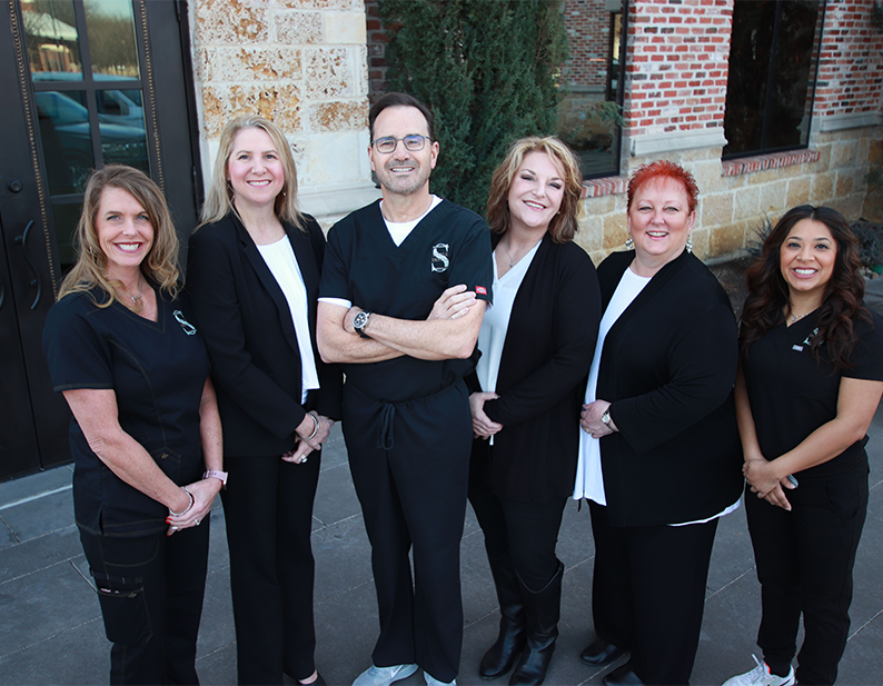 Coppell oral surgeon and team members smiling outside of oral surgery office