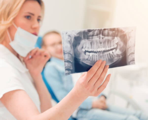 Oral surgery team member and patient looking at digital x-rays before wisdom tooth extractions