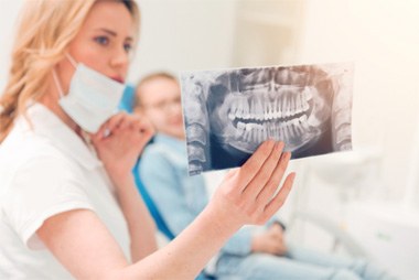 a dentist presenting an X-ray of a patient’s wisdom teeth