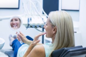 mature woman in dental chair looking in mirror