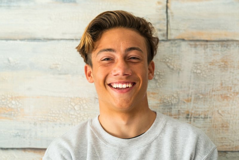 Teenager in grey shirt standing and smiling