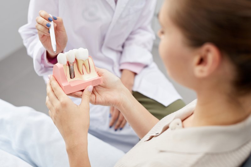 A dental patient holding a dental implant model