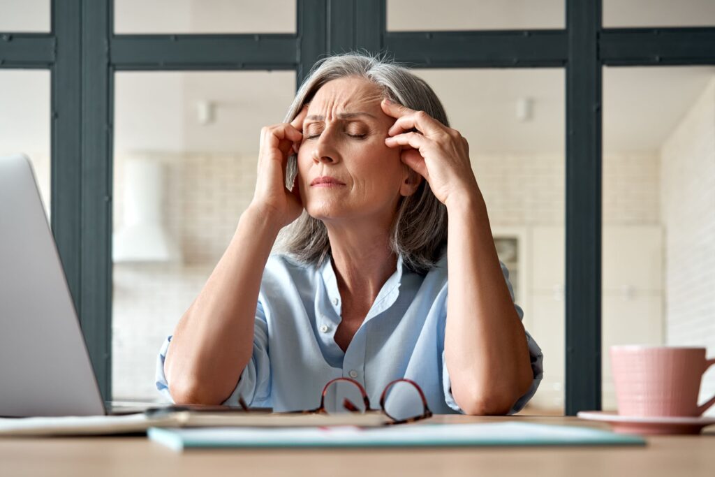 Older woman with gray hair took off glasses to massage temples