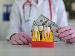 model of a dental implant with the dentist holding money